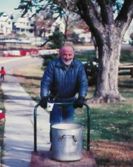Pastor Paul S Arnopoulos is pushing a small flat bed cart with the bottom half of a double cooker filled with hot water at the Voter Registration Picnic.