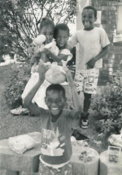 Young children having fun picnicing on the church wall with a very large squirt gun.