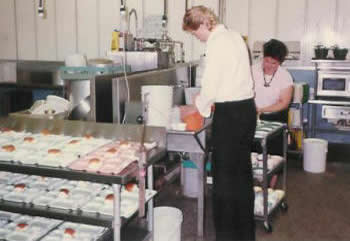 Volunteers Alicia Saunders and Paul Hanson prep trays for Senior's Day.