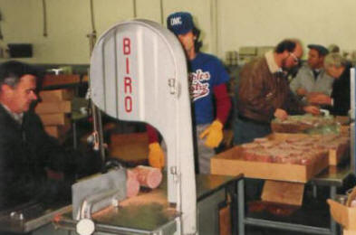 Volunteers cut 10 pound frozen loafs of beef into smaller 1 pound packages for the Grocery Shelf.