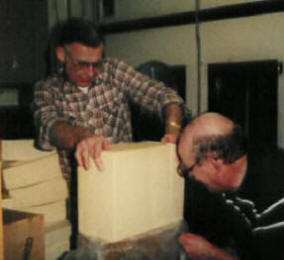 Church volunteers cut 40 pound blocks of frozen cheese into 1 pound chunks using a wire.