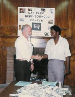 Pastor Paul S Arnopoulos delivers a table full of dollar bills to Oak Park Neighborhood Center Northside Executive Director.