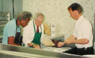 Charity Daniels, Skip Humphrey and his aid prep lunch trays for Senior's Day.