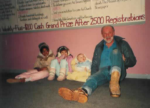 Pastor Paul S Arnopoulos with small children sittiing on the floor in 1985.